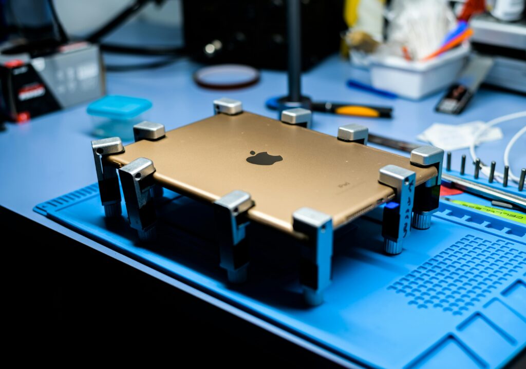 A close-up view of a tablet undergoing repair in a tech workshop with specialized tools.